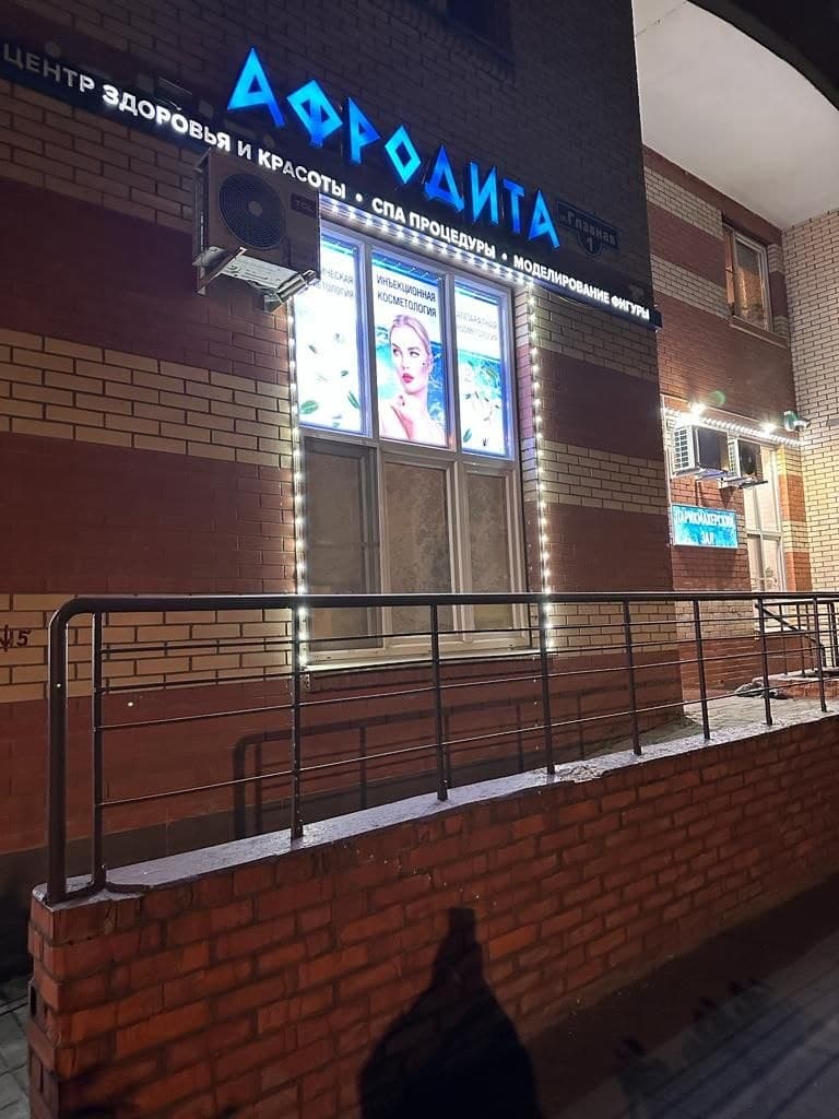 светящаяся вывеска афродита и световые панели в окнах центра красоты в вечернее время