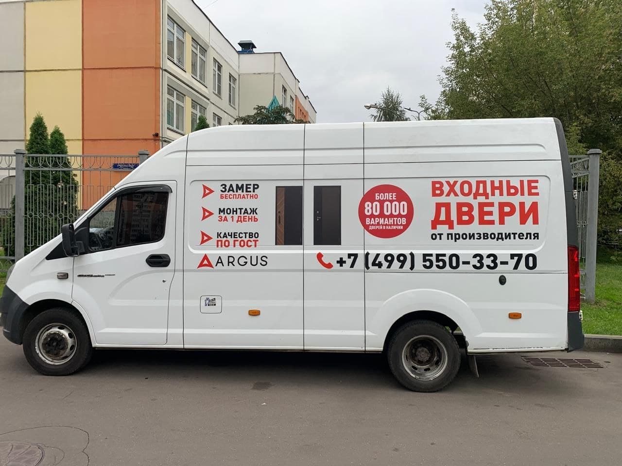 белый фургон с рекламой входных дверей argus и контактами компании на улице