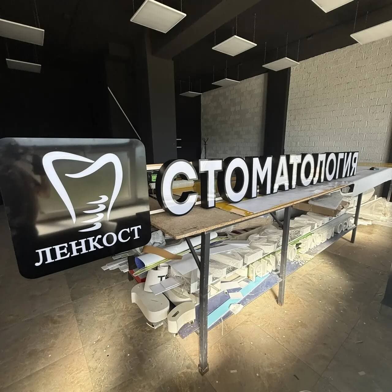 Световой короб ЛЕНКОСТ и объемные буквы СТОМАТОЛОГИЯ на сборочном столе в цеху