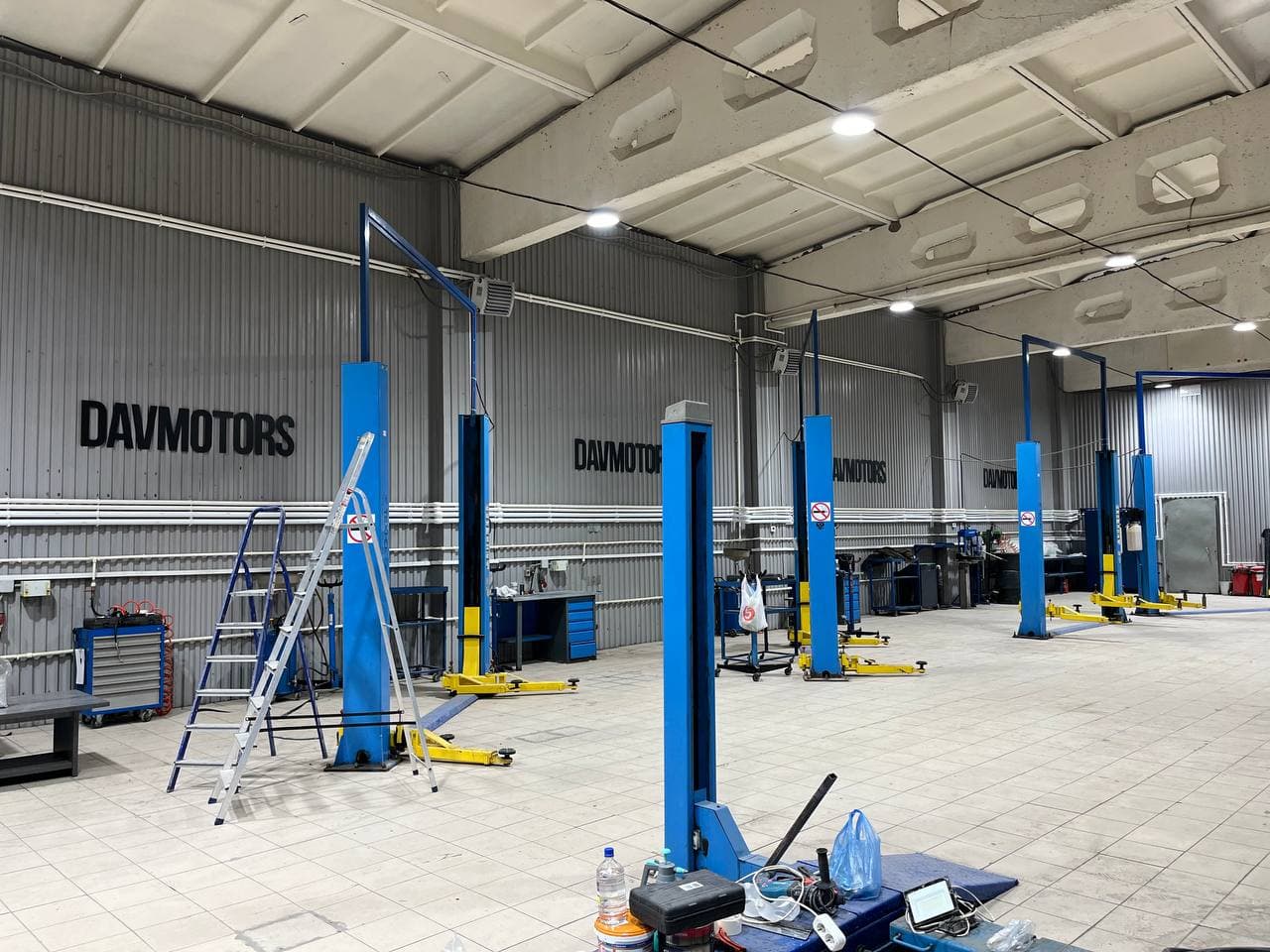Черные буквы DAVMOTORS из ПВХ на стене автосервиса над автомобильными подъемниками